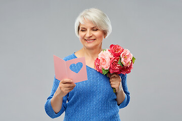 Image showing happy senior woman with flowers and greeting card