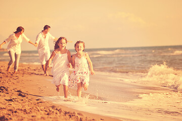 Image showing happy family playing with dog on beach