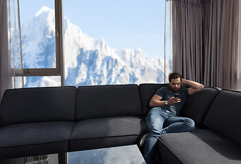 Image showing young casual man using a mobile phone at home