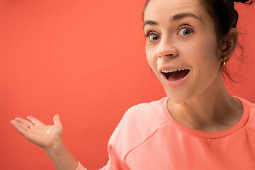 Image showing Beautiful woman looking suprised isolated on coral