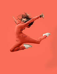 Image showing Freedom in moving. Pretty young woman jumping against coral background