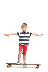 Image showing Full length portrait of an adorable young boy riding a skateboard isolated against white background