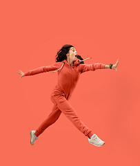 Image showing Freedom in moving. Pretty young woman jumping against coral background