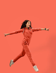 Image showing Freedom in moving. Pretty young woman jumping against coral background