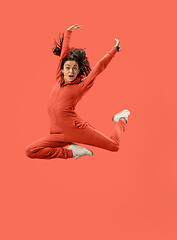 Image showing Freedom in moving. Pretty young woman jumping against coral background