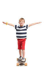 Image showing Full length portrait of an adorable young boy riding a skateboard isolated against white background