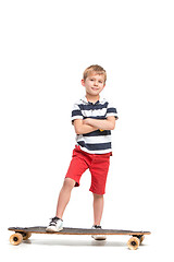 Image showing Full length portrait of an adorable young boy riding a skateboard isolated against white background