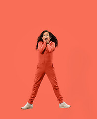 Image showing Freedom in moving. Pretty young woman jumping against coral background