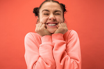 Image showing The happy woman standing and smiling against coral background.