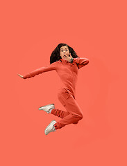 Image showing Freedom in moving. Pretty young woman jumping against coral background