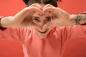 Image showing Portrait of attractive cute girl with bright makeup with love isolated over coral background