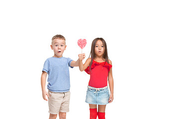 Image showing Full length portrait of cute little kids in stylish clothes looking at camera and smiling with candy