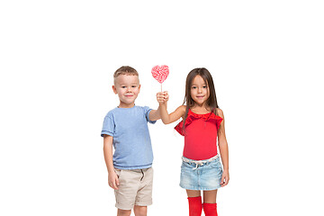 Image showing Full length portrait of cute little kids in stylish clothes looking at camera and smiling with candy