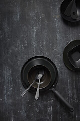 Image showing Dinner served table with black cookware on the same color background.