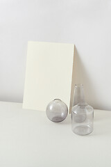 Image showing Empty glass vases and natural craft paper sheet card for text.