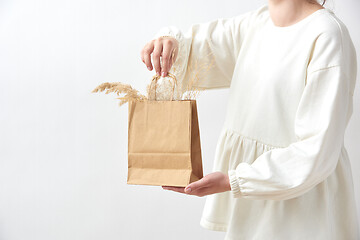 Image showing Female holds in her hands paper eco bag with dry natural plant twigs.