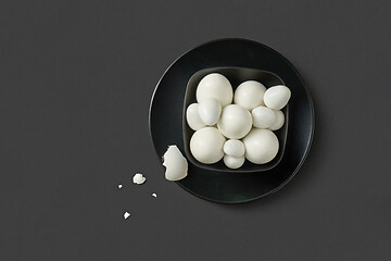 Image showing Fresh farm chicken and quail eggs boiled on a black plate on a dark background.