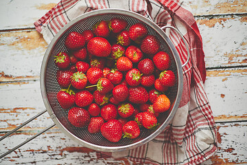 Image showing Freshly harvested strawberries. Metal colander filled with juicy fresh ripe strawberries on an table
