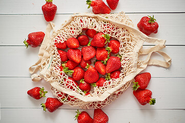 Image showing Fresh strawberries in eco-friendly package on white wooden background. Vegetarian organic meal