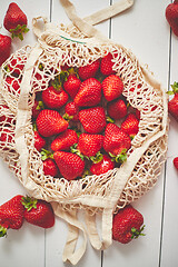 Image showing Fresh strawberries in eco-friendly package on white wooden background. Vegetarian organic meal