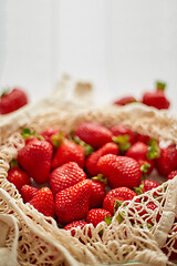 Image showing Fresh strawberries in eco-friendly package on white wooden background. Vegetarian organic meal