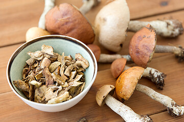 Image showing dried mushrooms in bowl on wooden background