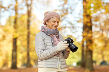 Image showing senior woman with photo camera at autumn park