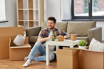 Image showing smiling man drinking beer and eating at new home