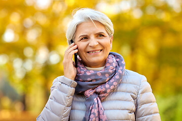 Image showing senior woman calling on smartphone at autumn park