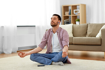 Image showing man in earphones listening to music and meditating
