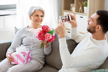 Image showing adult son photographing senior mother at home