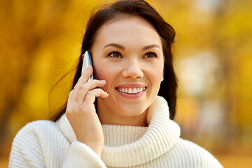 Image showing woman calling on smartphone in autumn park