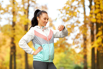 Image showing woman looking at fitness tracker in autumn park