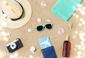 Image showing travel tickets, camera and hat on beach sand