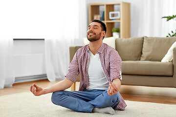 Image showing man meditating in lotus pose at home