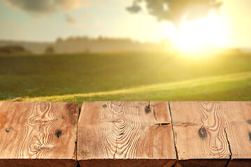 Image showing Rough wooden table on natutal rural sunset landscape a for display and montage your products.