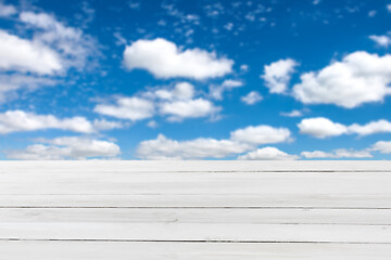 Image showing Blank grey wooden table for display or montage your products on a blurred blue cloudy sky background.