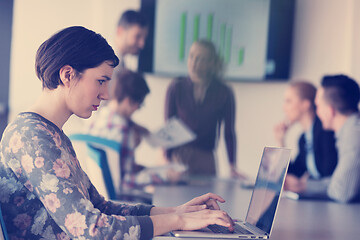 Image showing young business woman at office working on laptop with team on me