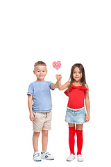 Image showing Full length portrait of cute little kids in stylish clothes looking at camera and smiling with candy