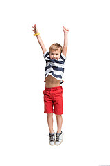 Image showing Adorable boy jumping and raises his hands up.