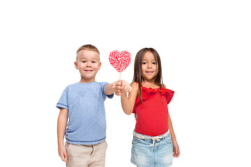 Image showing Full length portrait of cute little kids in stylish clothes looking at camera and smiling with candy