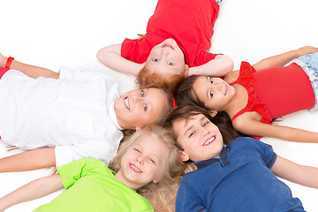 Image showing Close-up of happy children lying on floor in studio and looking up