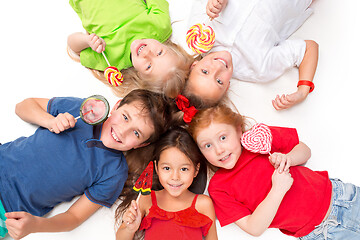 Image showing Close-up of happy children lying on floor in studio and looking up