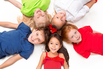 Image showing Close-up of happy children lying on floor in studio and looking up
