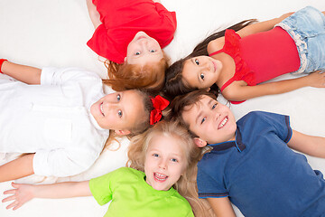 Image showing Close-up of happy children lying on floor in studio and looking up