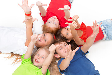 Image showing Close-up of happy children lying on floor in studio and looking up