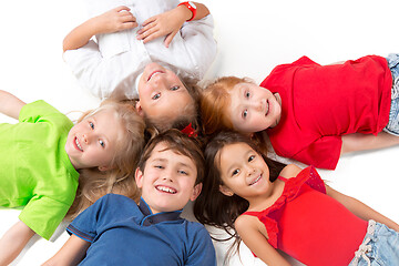 Image showing Close-up of happy children lying on floor in studio and looking up