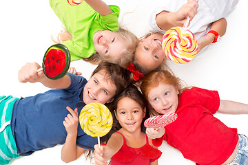 Image showing Close-up of happy children lying on floor in studio and looking up