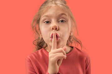 Image showing Young girl with her finger on her mouth on coral background