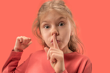 Image showing Young girl with her finger on her mouth on coral background